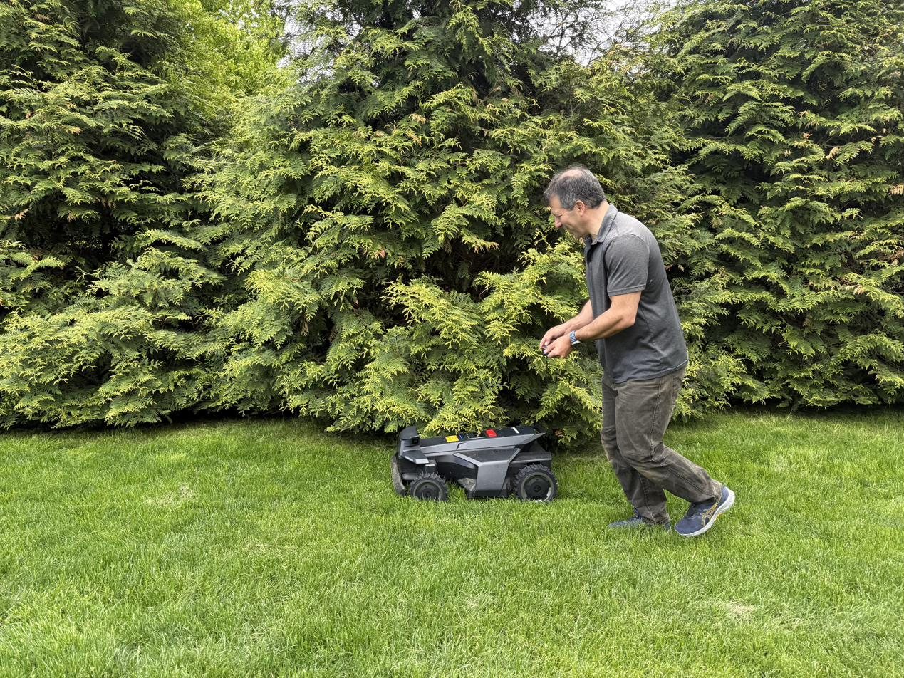 A Mosey technician servicing a robotic mower on a customer property